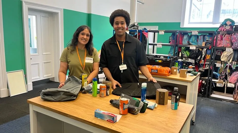 Two people smiling making up welcome packs